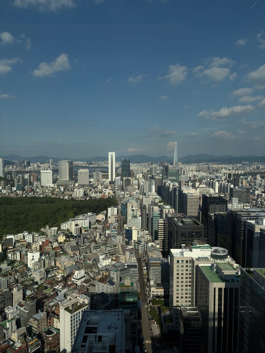 Seoul seen from a high floor, with a park on the left and buildings to the horizon
