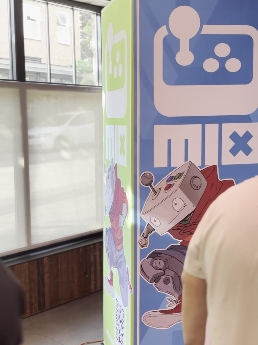 The MIX standee, with its arcade-controller logo and robot mascot, at the showcase venue